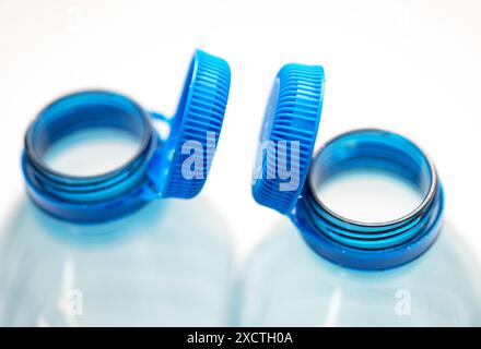 This close-up captures the detail of blue tethered caps on clear plastic bottles, reflecting EU environmental regulation standards. Stock Photo