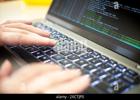 A person's hands are typing on a laptop displaying hacker code, highlighting issues of cyber security, privacy threats, and server processes. A cyber Stock Photo