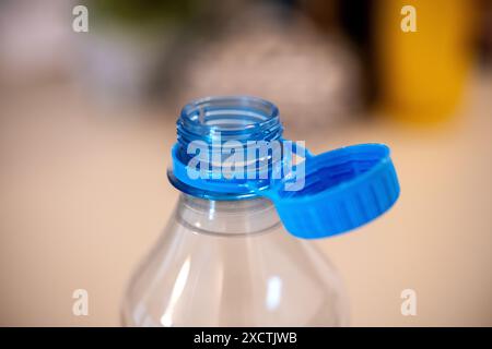 A close-up shot focuses on a blue tethered cap attached to a transparent water bottle, highlighting the EU's new environmental policies aimed at reduc Stock Photo