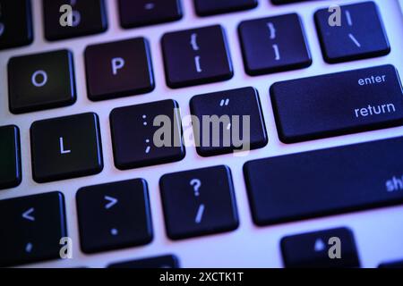 A detailed view of a modern keyboard highlighting the enter and return keys under a blue backlight. Hacker tools, virus, data breach, security breach Stock Photo