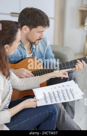 man learning his girlfriend how to play guitar Stock Photo