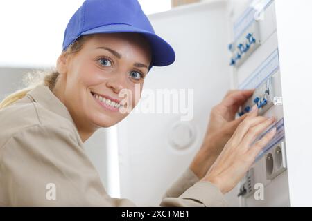 happy woman inspecting fuse board Stock Photo