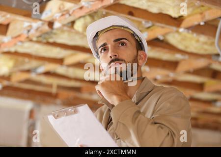 builder thinking about something while holding clipboard Stock Photo