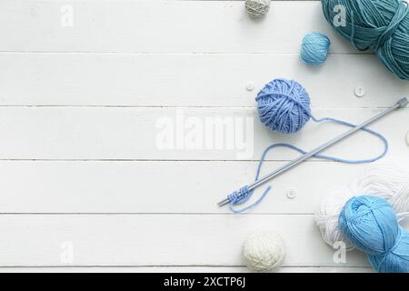 Yarn balls, knitting needles and buttons on white wooden background Stock Photo