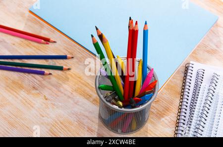 Multicolored wooden pencils on desk with papers and notebooks Stock Photo