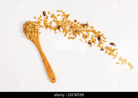 Granola with mixed nuts and died fruits in a wooden spoon and scattered on the white table Stock Photo
