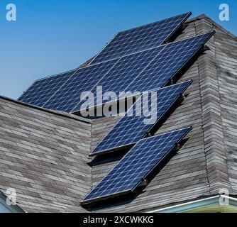 Solar panels arranged on a high pitched roof with several sides. Stock Photo