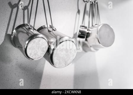 Stainless Steel Cooking Pots Hanging On A White Wall Stock Photo