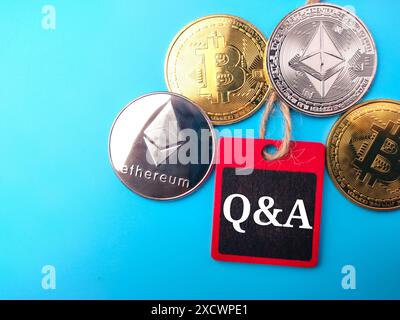 Top view golden bitcoin, silver ethereum and colored board with text Q AND A on blue background. Stock Photo