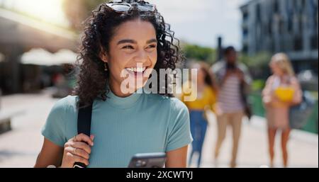 Education, phone and thinking with student laughing on campus of college or university for learning. Commute, development and funny with happy woman Stock Photo