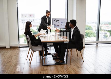 Businessman handing out papers during office meeting Stock Photo