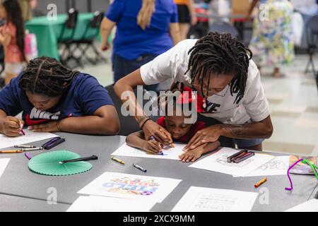 A mother helping her daughter color at a community event on Family Field Day in Fort Worth, TX Stock Photo
