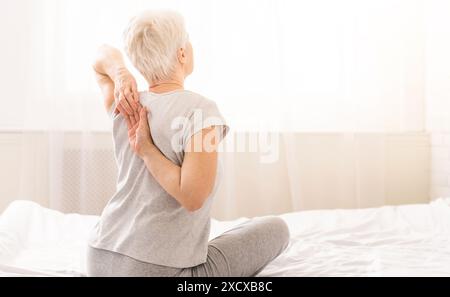 Elderly woman touching her hands behind her back Stock Photo