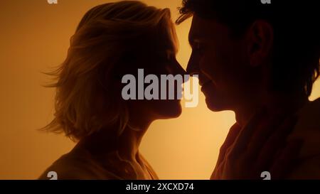 Lovely couple kissing and touching each other during romantic date in orange neon light studio  Stock Photo