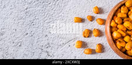 Roasted corn nuts with sauce in wooden bowl on white stone table Stock Photo