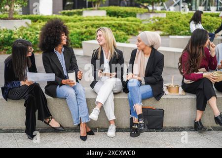 Multiethnic business women doing lunch break outdoor from office building - Summer and job lifestyle concept - Focus on arabian girl face Stock Photo