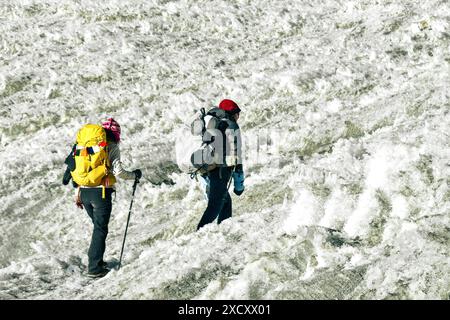 Two trekkers trekking in Himalayas mountains through Chola glacier pass to Gokyo Ri. Nepalese male guide leading tourist client in Sagarmatha national Stock Photo