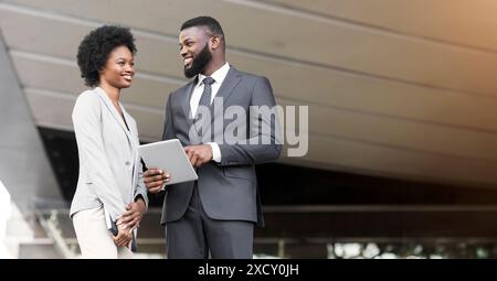 Happy young fellow workers browsing internet on digital tablet outdoors Stock Photo