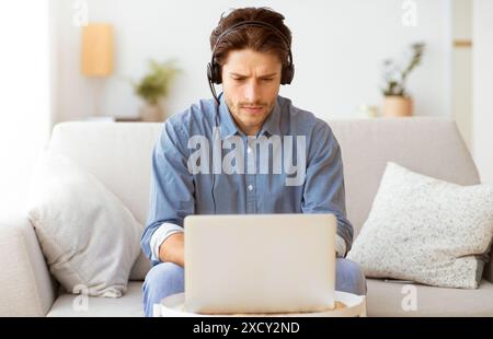 Man Working On Laptop While Wearing Headphones Stock Photo