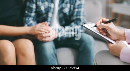 Therapist Taking Notes While Couple Sits Together In Counseling Session Stock Photo