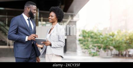 Happy young fellow workers browsing internet on digital tablet outdoors Stock Photo