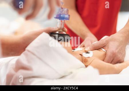 Hands of paramedic of emergency medical service during training resuscitation training on newborn dummy. Stock Photo