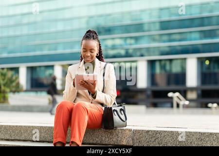 Black Woman Using Tablet Outside Office Building for Business and Entrepreneurship Stock Photo