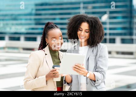Two Businesswomen Collaborating Outdoors on Digital Tablet During Work Meeting Stock Photo
