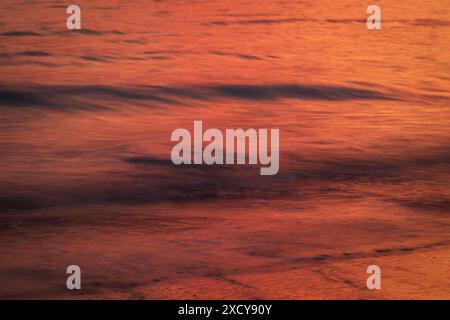 Ocean and small motion blurred waves at sunset. Natural tropical travel, vacation and summer background with copy space. Stock Photo