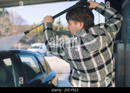 Cleaning car using active foam. Man washing his car on self car-washing. Stock Photo