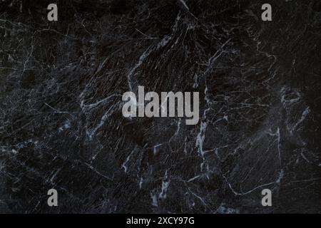 Close-up of dark gray, almost black, smooth and natural textured marble pattern background. Abstract full frame textured background with copy space. Stock Photo