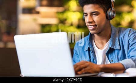 Closeup of Young Guy Wearing Headphones Working on Laptop Stock Photo