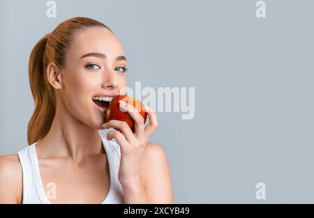 Woman With Long Blonde Hair Bites Into Red Apple Stock Photo