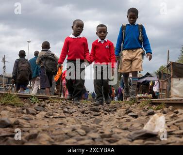 Schoolchildren walking along a railway line to or from school in Kibera slum Nairobi Kenya Stock Photo