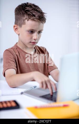 Distance learning online education. A schoolboy is studying at home using a laptop. Home distance learning. Stock Photo