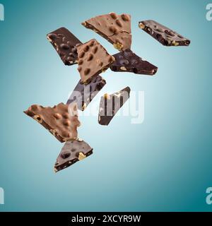 Milk and dark pieces of hazelnut chocolate flying on blue background. Stock Photo