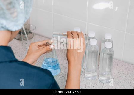 Women in laboratory examines quality of water with glass tube filled, blue chemical liquid for research and analysis in lab Stock Photo