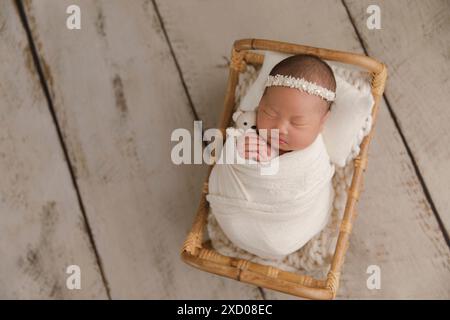 Top view of a newborn baby sleeping on a bed under beige blanket and a bendable headband flower on her head. Copy space. Newborn baby care concept. Stock Photo