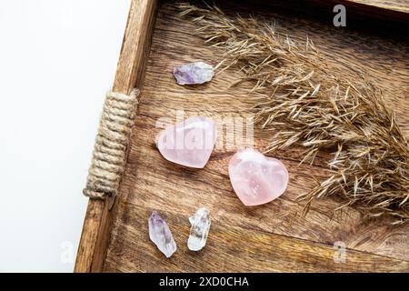 Pink color heart shape rose quartz on wood tray at home can also be used to attract love. Stock Photo