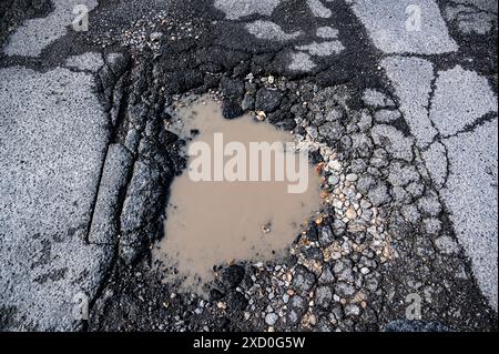 Huge pothole filled with rain water in a UK town center Stock Photo