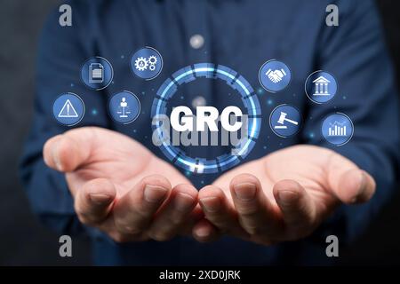 GRC, Governance Risk and Compliance concept. Businessman holding GRC icon on digital screen, structuring to align IT with business goals for optimal p Stock Photo