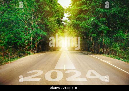 New year 2024 or straight forward concept. Text 2024 written on the road in the middle of asphalt road with at sunset. Concept of planning, goal, chal Stock Photo