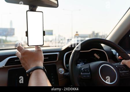 A person is driving a car with a phone mounted on the dashboard. The phone is displaying a blank screen, clipping path, indicating that it is not curr Stock Photo