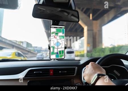 A person is driving a car with a phone mounted on the dashboard. The phone is displaying a map of the area. GPS concept. Stock Photo