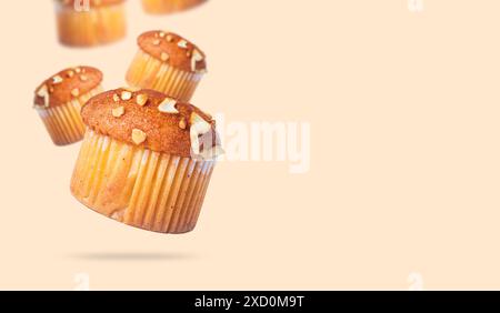 Cupcakes with nuts flying in the air on a beige background. Muffins with nuts Stock Photo