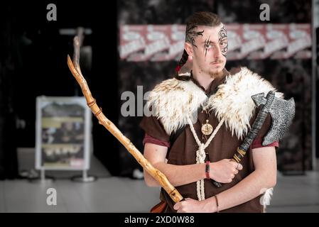A young man in medieval attire holding a staff and wearing a mask Stock Photo