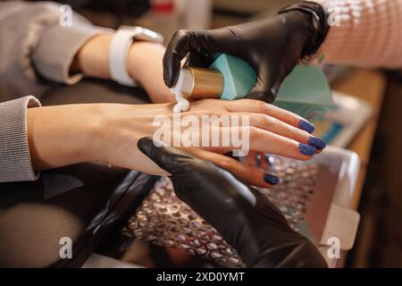 manicurist applies cream to client's hands for hand care in beauty salon, concept of skin problem on hands Stock Photo