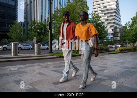 Cheerful joyful African American couple teens in love having fun walking strolling around city town Stock Photo