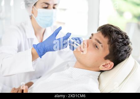 Young man having face care by means of injection in aesthetic clinic Stock Photo