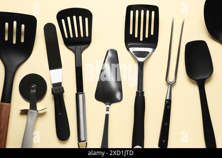 Different spatulas and other kitchen utensils on beige background, flat lay Stock Photo